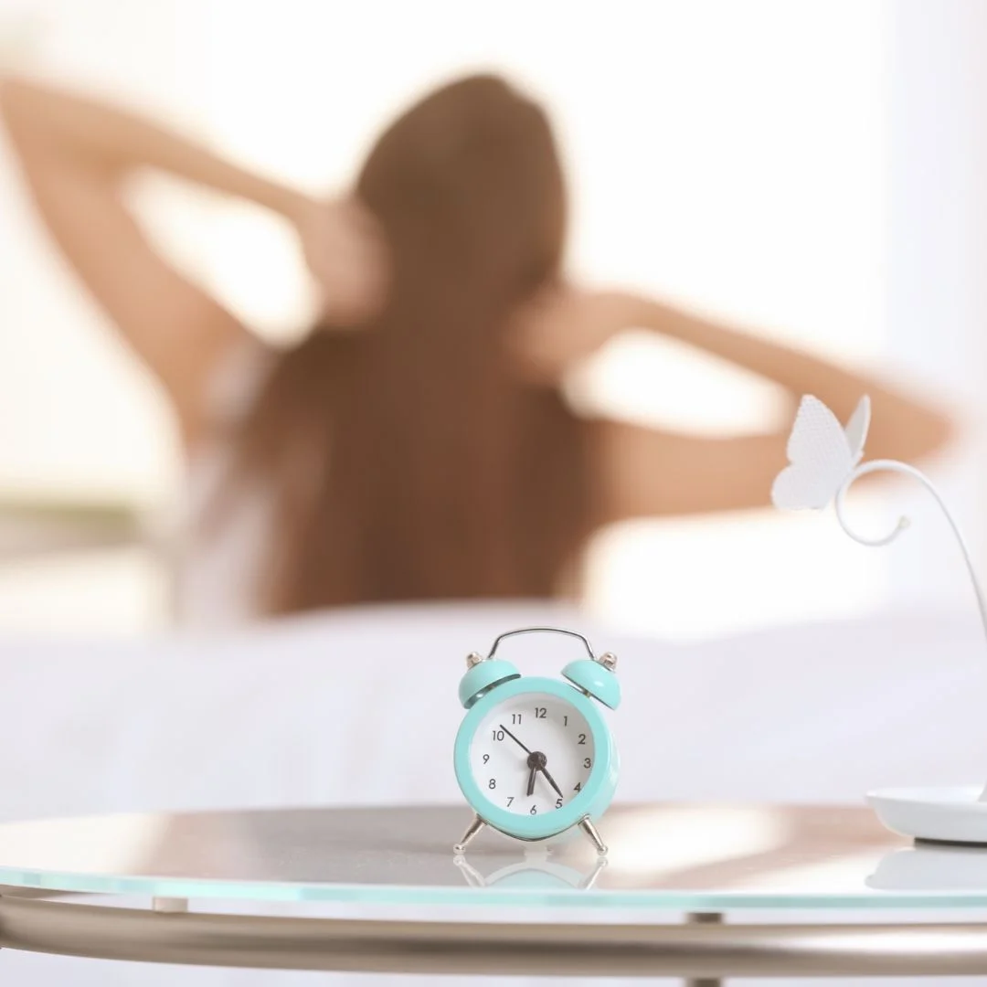 Girl waking up in the morning with a clock in the background showing early morning time