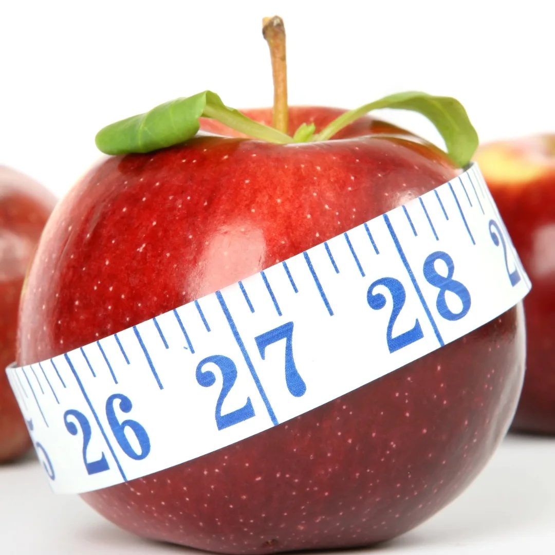 A red apple with a measuring tape wrapped around it, symbolizing diet or healthy eating.