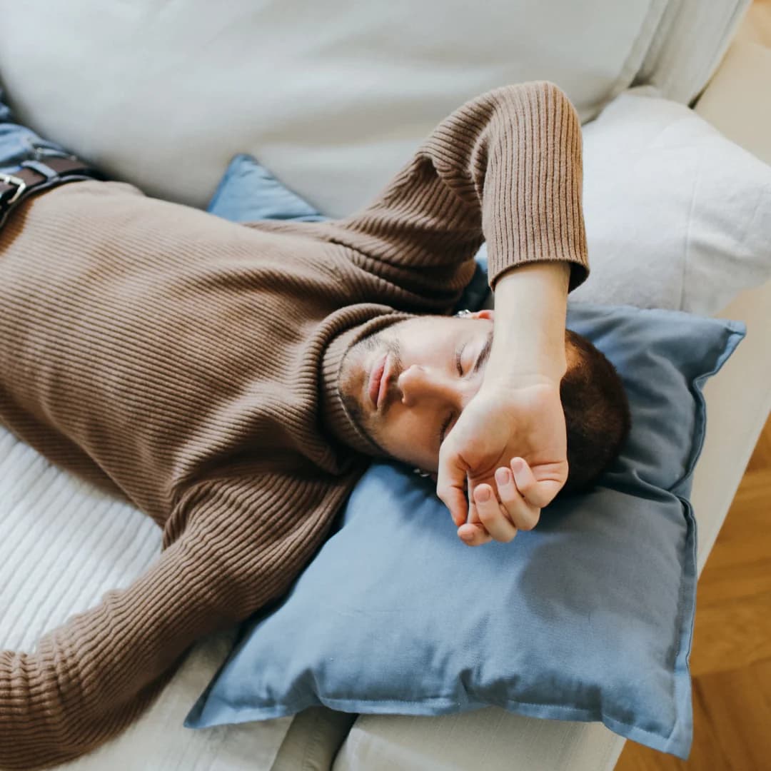 a man sleeping on sofa with a pillow on his head