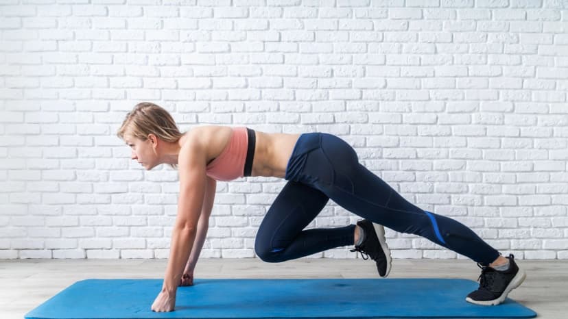Woman performing mountain climbers on yoga mat at home