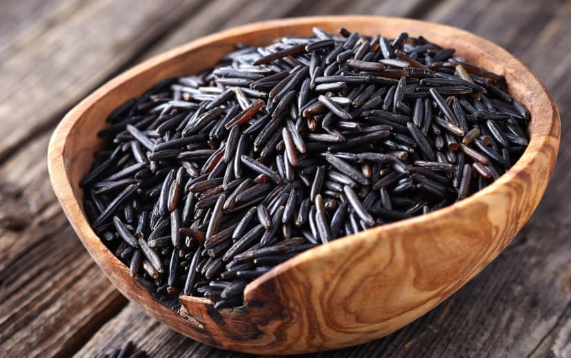 front view wild rice in the wooden bowl placed in the wooden table