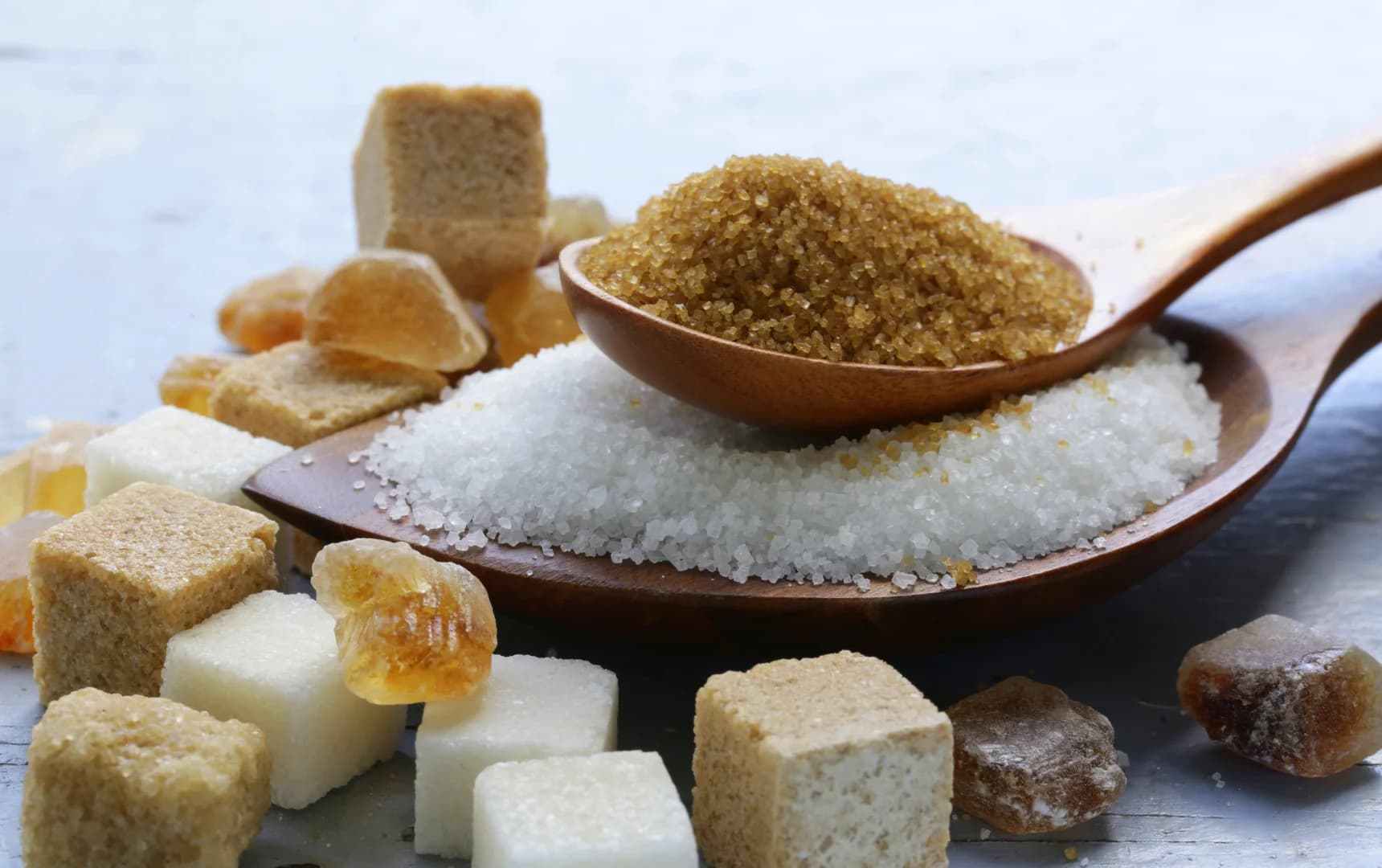 top view of wooden sugar spoon small wooden spoon is to of the other spoon sugar cubes in the background