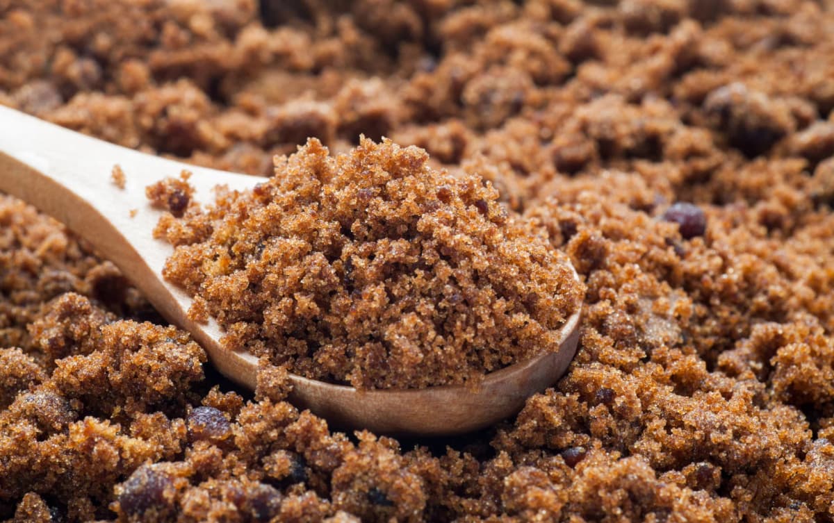 top view wooden spoon of brown sugar also brown sugar in the backgrownd
