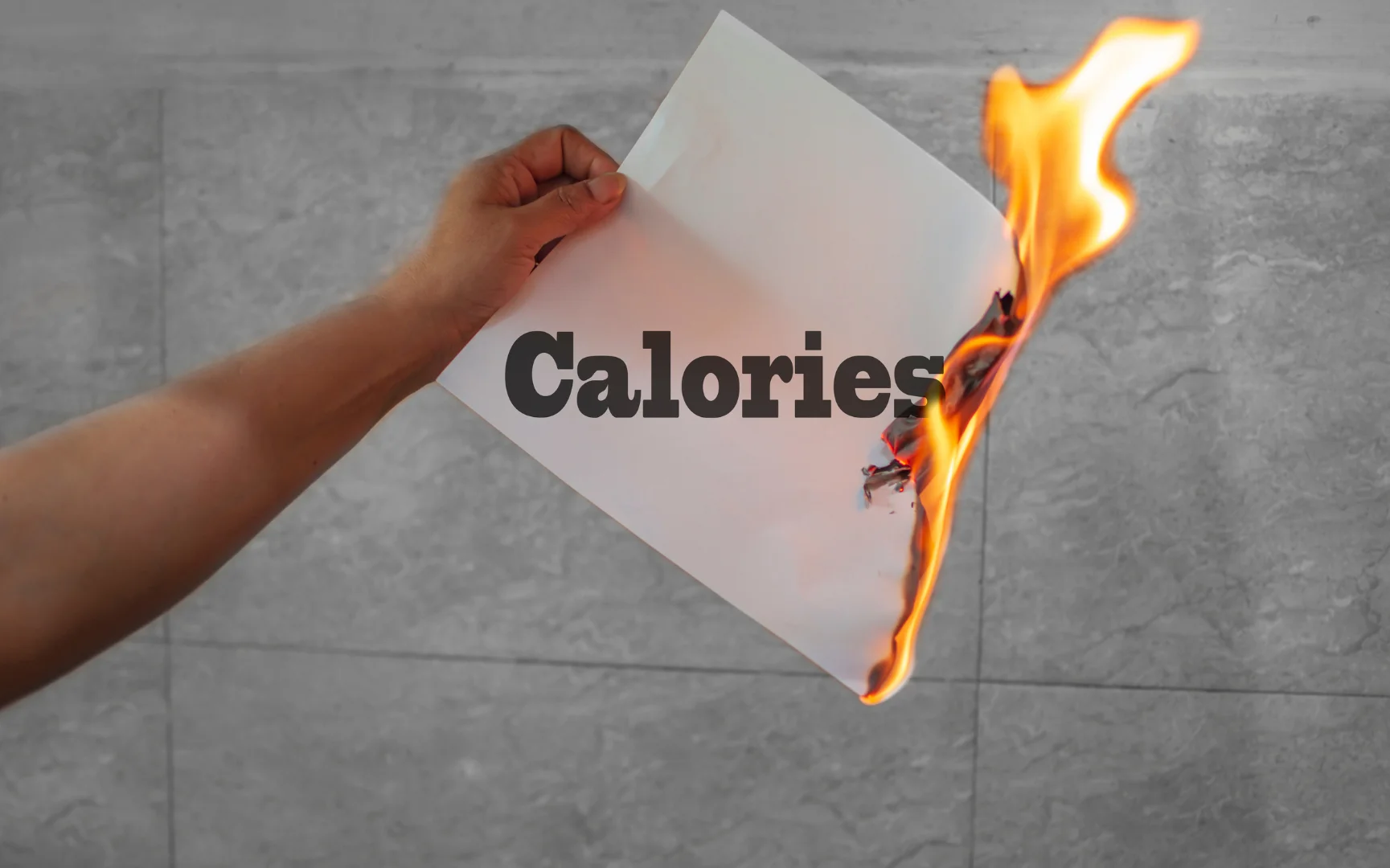 Person holding burning paper with calories written on it
