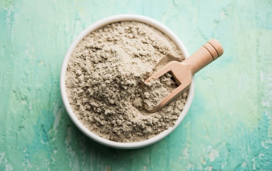 top view bowl of bajra wheat flour wooden scoop on the top