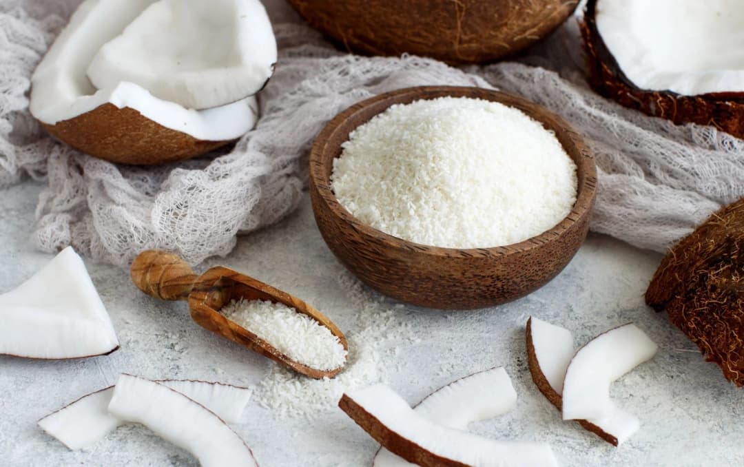 top view of coconut flour in the coconut shell coconut slices on background