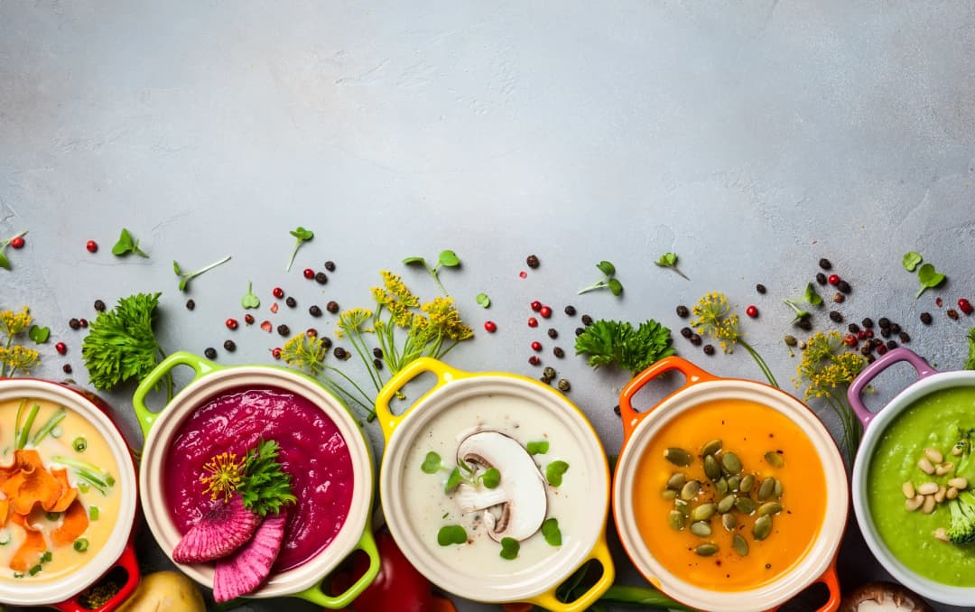top view of 5 diffrent types of soups served in hotpots garnished items on the background