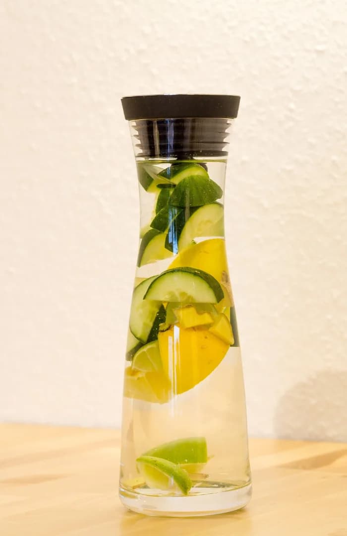 Front view of detox water in glass bottle cucumber and lemon slices inside