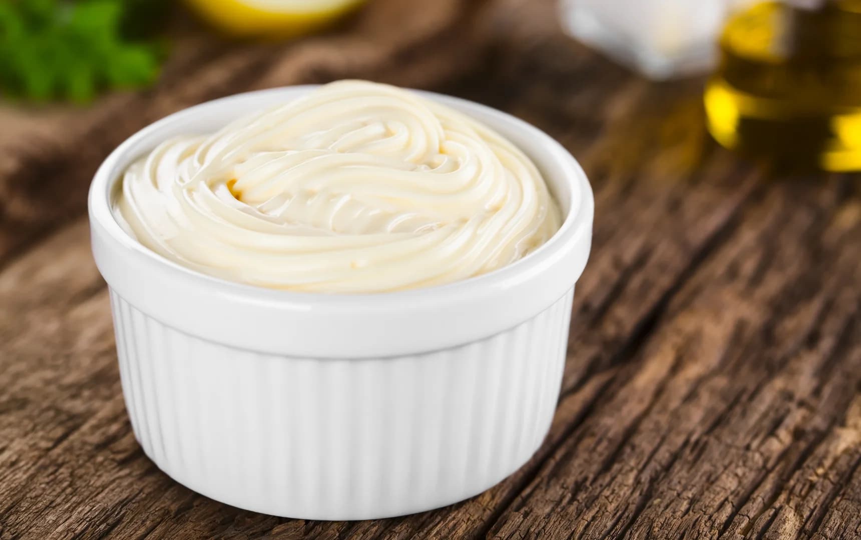 Healthy homemade mayonnaise served in a small dip bowl on a wooden cutting board front view