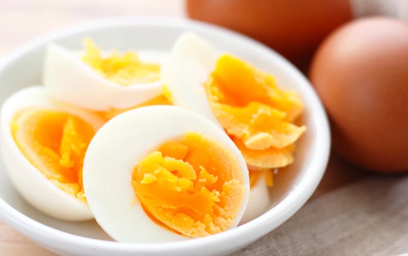 boiled egg served in white bowl also raw eggs in the background