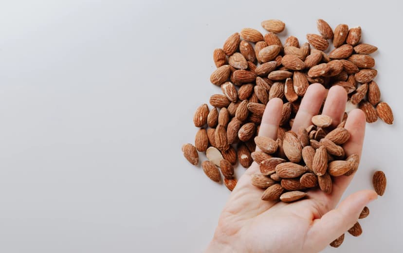 top view of some almonds in human hand and more almonds in the background