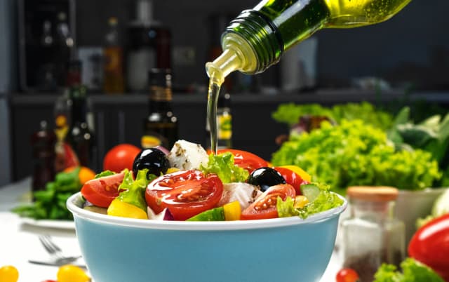 front view plastic bowl of salad dipping olive oil for garnishing salad ingredients in the background