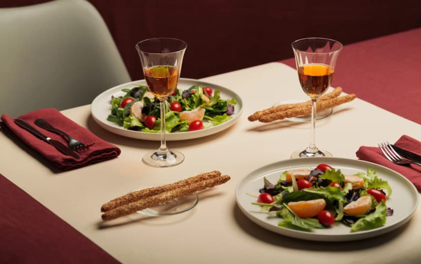 healthy salad in the dinner table served in two plates also 2 wine glasses and crockery