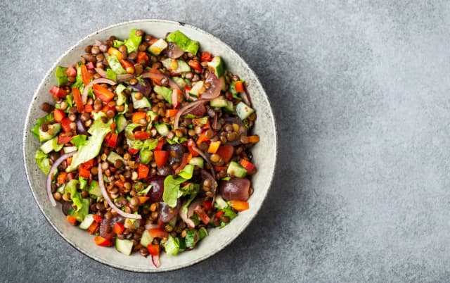 top view of Lentil and Vegetable Salad mix with onion lentil, cucumbers, tomatoes, lettuce served in white plate
