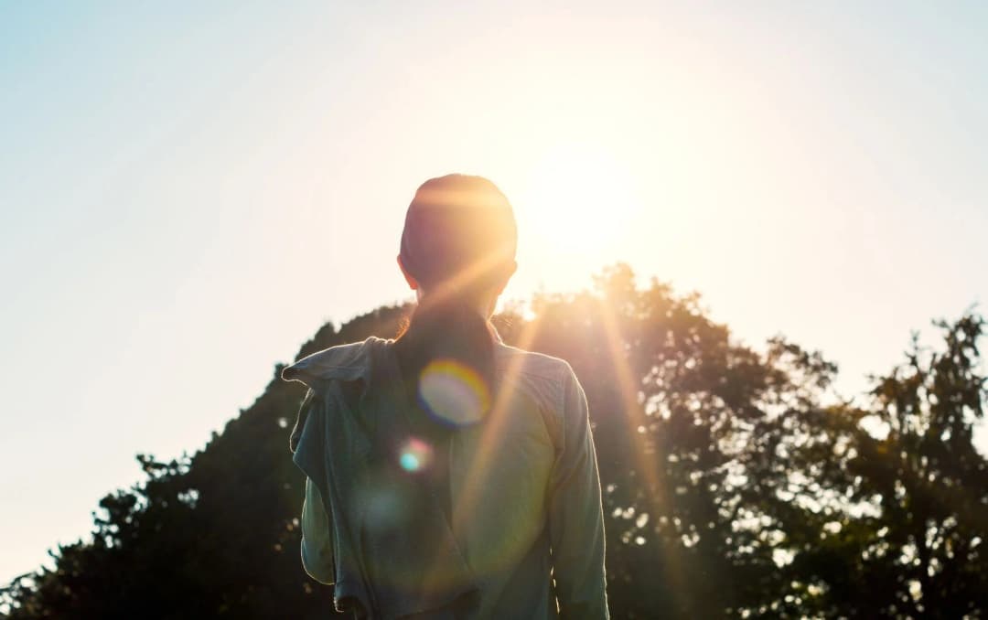 back view of lady doing looking at the sun during walk in the morning