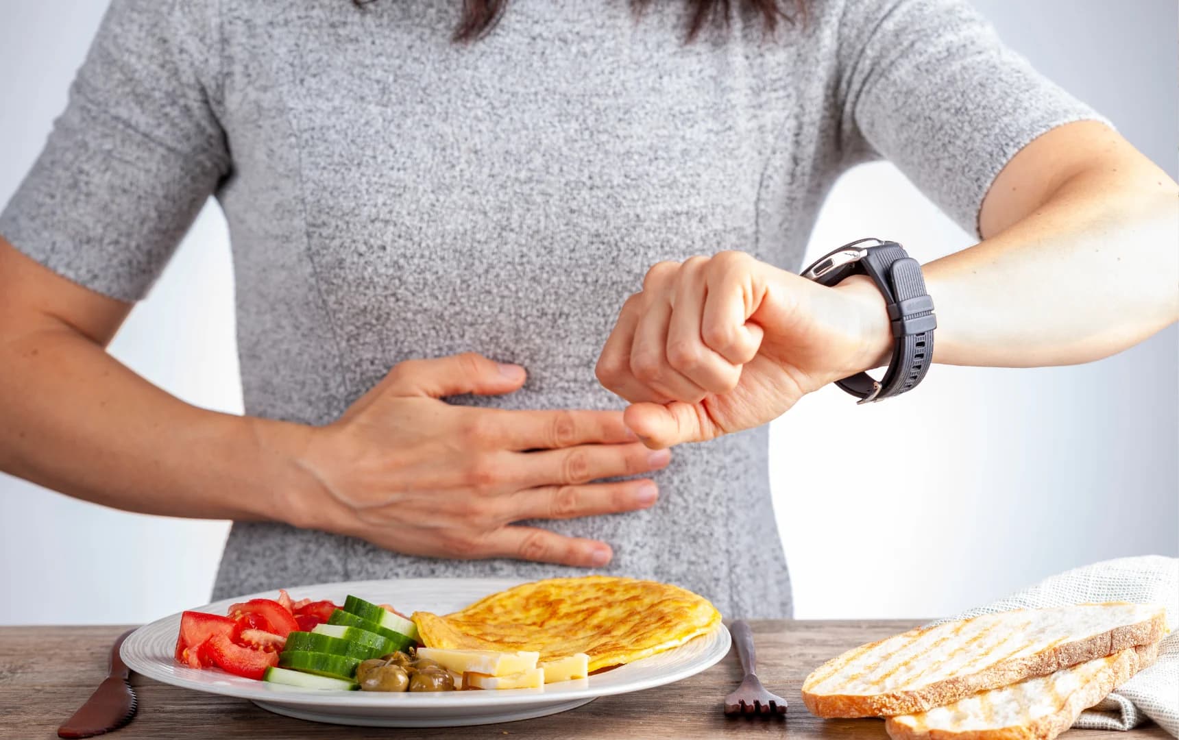 Person checking time on wristwatch before starting meal while practicing intermittent fasting