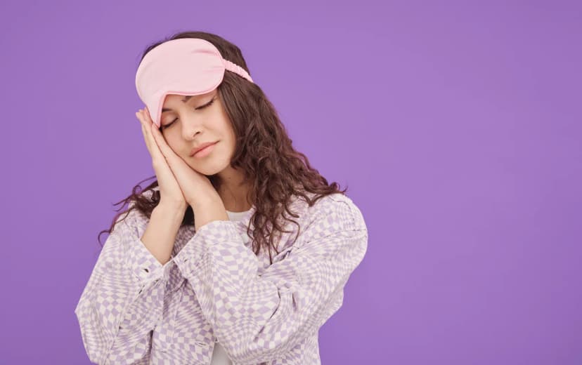 a girl standing and pretending action of sleeping and a sleeping eye mask on her forehead