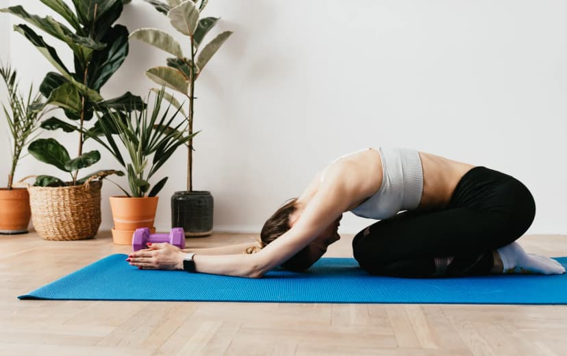a lady doing child pose of yoga in the yoga mat morning view in the house